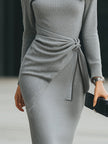 Elegant FJØRNA knit midi dress with side tie detail, showcasing a fitted silhouette and soft, textured fabric.