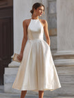 FJØRNA halter-neck pleated midi dress for women, featuring a flowing design with a fitted waist and elegant pleats.