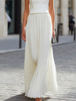 FJØRNA sleeveless boat neck pleated maxi dress displayed on a hanger, featuring flowing fabric and elegant pleats.