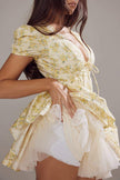 Yellow Emily Floral V-neck Corset Mini Dress by FJØRNA, featuring a fitted bodice and floral pattern, displayed on a dress form.
