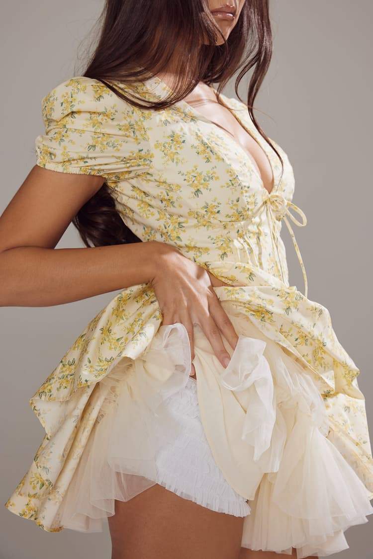 Yellow Emily Floral V-neck Corset Mini Dress by FJØRNA, featuring a fitted bodice and floral pattern, displayed on a dress form.