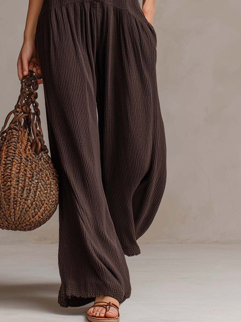 FJØRNA brown sleeveless knitted jumpsuit with ruffle neck and retro style, featuring a fitted waist and wide-leg pants.