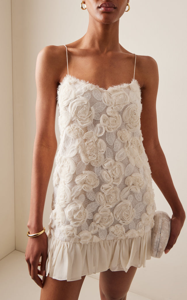 White rosette georgette frilled mini dress by FJØRNA, perfect for wedding guest attire, featuring delicate ruffles and floral details.
