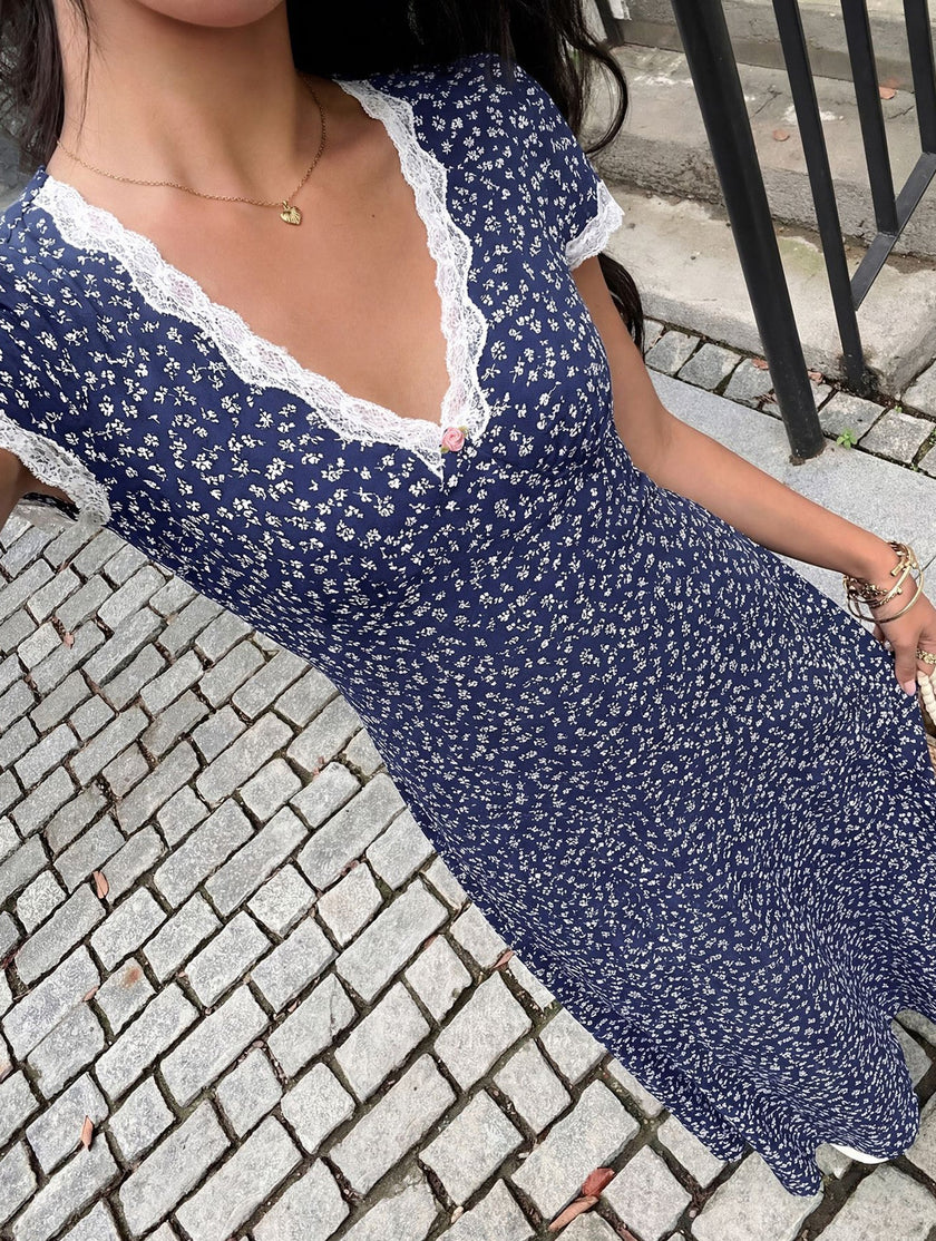 White FJØRNA lace patch floral V-neck maxi dress with intricate lace details and flowing fabric, perfect for elegant occasions.