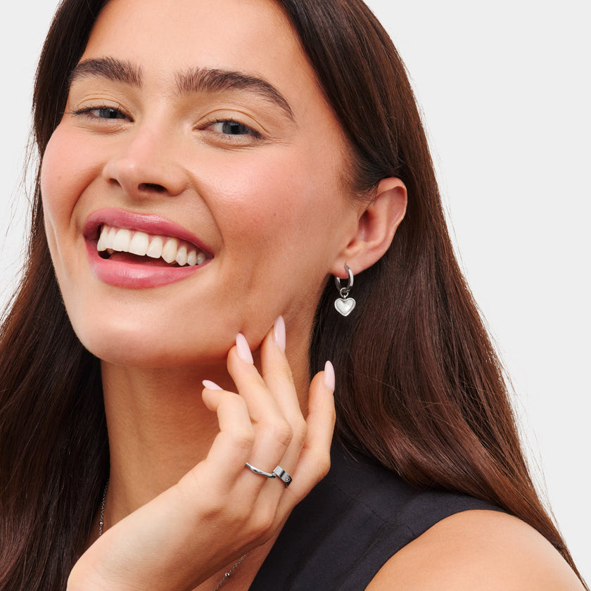 Silver FJØRNA White Quartz Heart Huggie Earrings for women, featuring delicate heart-shaped white quartz charms.