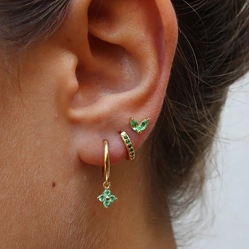 FJØRNA unisex piercing set with gold and green accessories, featuring stylish earrings and nose rings for women.