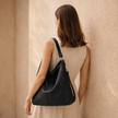 Black FJØRNA faux leather hobo shoulder bag for women with a spacious design and matching pouch, stylish vegan bag for everyday use.