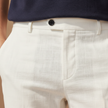 White FJØRNA linen trousers for men, relaxed fit pants with a classic style, displayed on a model.