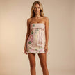 FJØRNA strapless floral mini dress with pleated fit, featuring a vibrant flower pattern and a fitted, stylish silhouette.