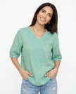 FJØRNA women's cotton V-neck blouse featuring a relaxed fit and soft fabric, displayed on a model.