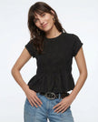 FJØRNA linen peplum blouse for women, stylish and lightweight top with a fitted waist and elegant design, shown on a model.