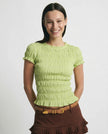 FJØRNA women's plaid top with ruffle detail, showcasing a stylish, casual blouse with checkered pattern and feminine accents.
