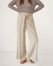 FJØRNA women's linen wide-leg trousers with elastic waist and ruffle detail, showcasing lightweight fabric and relaxed fit.