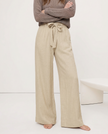 FJØRNA women's linen wide-leg trousers with elastic waist and ruffle detail, showcasing soft, textured fabric and relaxed fit.