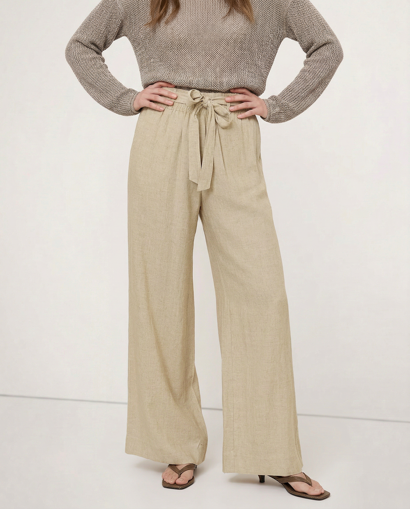 FJØRNA linen wide-leg women's trousers with elastic waist and ruffle detail, showing fabric texture and relaxed fit.