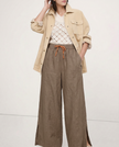 FJØRNA linen wide-leg women's trousers with drawstring, showing fabric texture and relaxed fit in a natural pose.