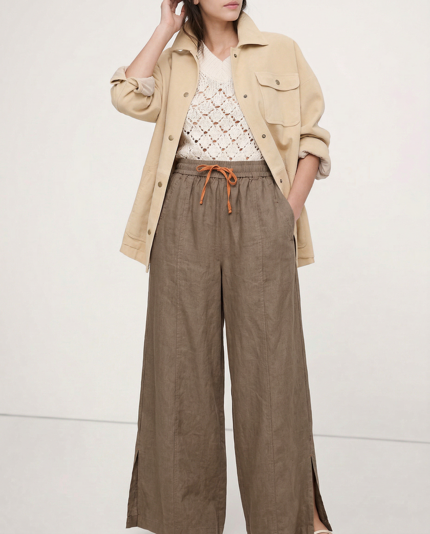 FJØRNA linen wide-leg women's trousers with drawstring, showing fabric texture and relaxed fit in a natural pose.