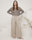 FJØRNA linen wide-leg women's trousers with elastic waist and ruffle detail, showcasing soft fabric and relaxed fit.