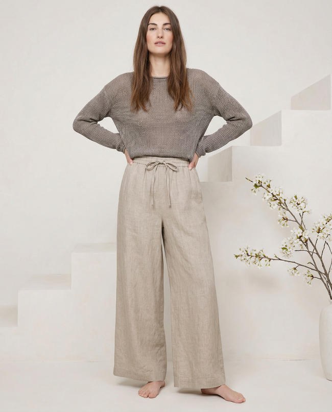 FJØRNA linen wide-leg women's trousers with elastic waist and ruffle detail, showcasing soft fabric and relaxed fit.