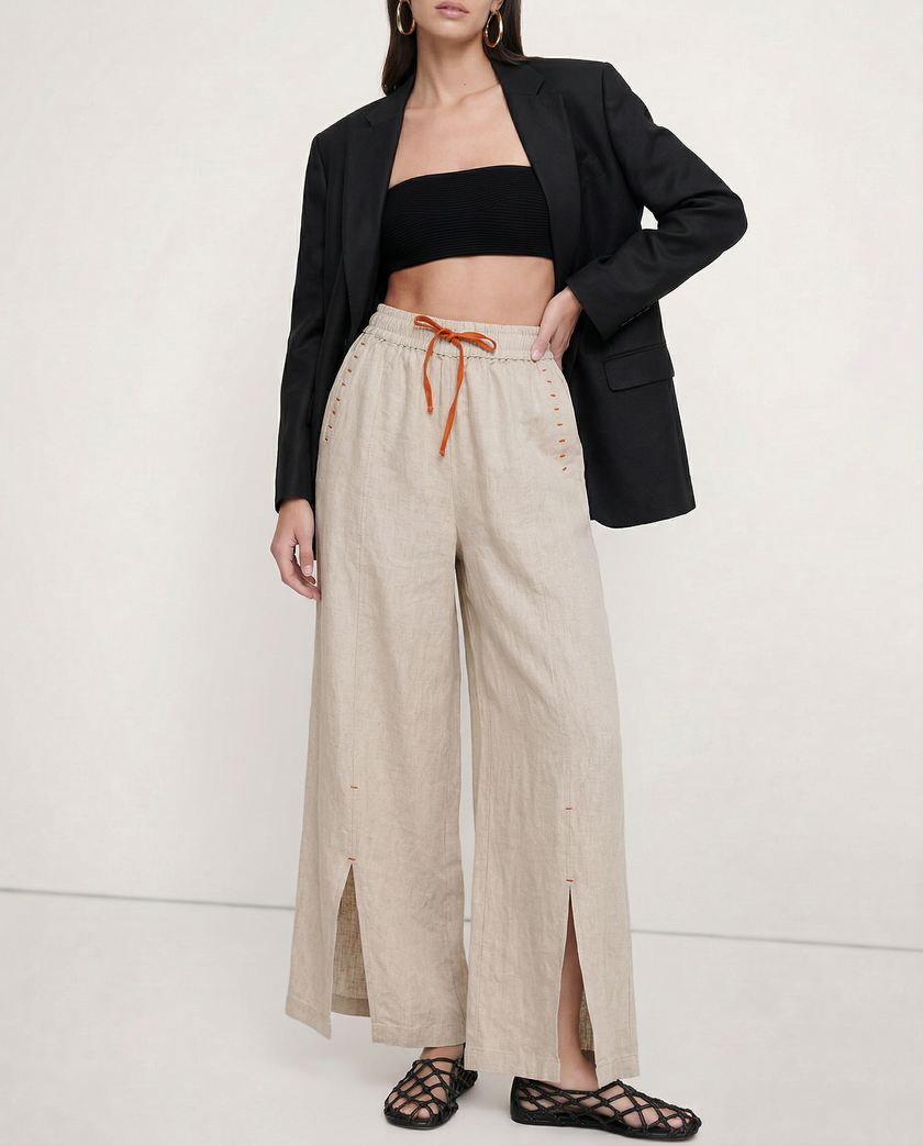 FJØRNA linen wide-leg women's trousers with drawstring, showing soft fabric and relaxed fit in a natural pose.