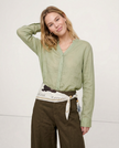FJØRNA women's linen V-neck shirt, lightweight and breathable top, worn by a model, featuring a relaxed fit and natural fabric texture.
