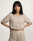 FJØRNA women's linen crop top with short sleeves, lightweight and breathable, shown on a model in a casual setting.