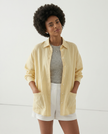 FJØRNA linen shirt with slit hem detail worn by model, featuring lightweight fabric and relaxed fit for a casual, stylish look.