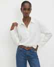 Women’s linen polo top by FJØRNA featuring a classic collar and relaxed fit, styled on a model in a casual setting.