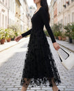 FJØRNA black stretch knit dress with 3D floral embroidered mesh overskirt, showcasing elegant floral design and fitted silhouette.