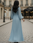Steel blue pleated midi dress by FJØRNA, featuring a flowing silhouette and elegant pleats, displayed on a hanger.
