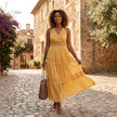 FJØRNA tiered lace maxi dress with V-neck and flowing skirt, featuring intricate lace details and a elegant, layered design.