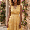 FJØRNA tiered lace maxi dress with V-neck and flowing skirt, displayed on a hanger with intricate lace details.