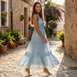 FJØRNA tiered lace maxi dress with V-neck and flowing skirt, featuring intricate lace details and a elegant, tiered design.