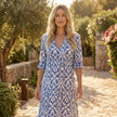 Printed V-neck midi dress by FJØRNA featuring a relaxed fit and flowing silhouette, shown hanging on a wooden hanger.