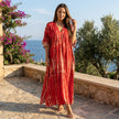 FJØRNA boho printed maxi dress with loose fit and V-neck, featuring floral patterns and flowing fabric, displayed on a hanger.