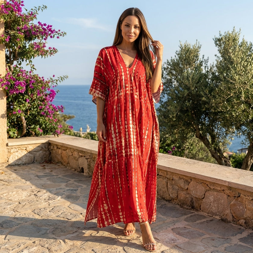 FJØRNA boho printed maxi dress with loose fit and V-neck, featuring floral patterns and flowing fabric, displayed on a hanger.