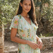 FJØRNA floral chiffon maxi dress with short sleeves and V-neck, flowing fabric, and a vibrant floral pattern.
