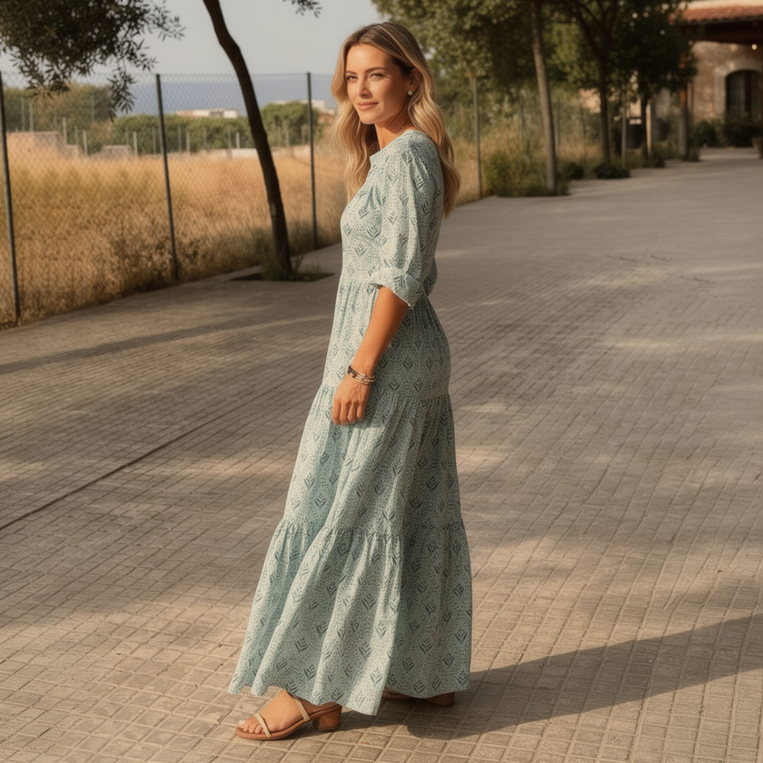 FJØRNA printed long sleeve maxi dress with V-neck, relaxed fit, featuring a flowing fabric and floral pattern.