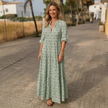 FJØRNA printed long sleeve maxi dress with V neck and relaxed fit, shown hanging on a mannequin with floral patterns.