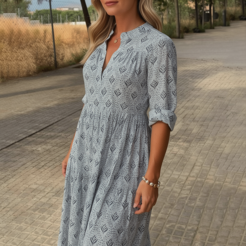 FJØRNA printed long sleeve maxi dress with V-neck, relaxed fit, and floral pattern, shown on a model.