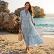 FJØRNA printed long sleeve maxi dress with V-neck and relaxed fit, shown hanging on a clothing rack.
