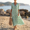 FJØRNA floral V-neck maxi dress with short sleeves and flowy fit, featuring a vibrant floral pattern and lightweight fabric.