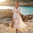 FJØRNA floral V-neck maxi dress with short sleeves, flowing fit, and vibrant flower print, perfect for warm weather occasions.