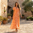 FJØRNA floral chiffon midi dress with short sleeves and a flowy skirt, featuring a vibrant floral pattern and elegant silhouette.