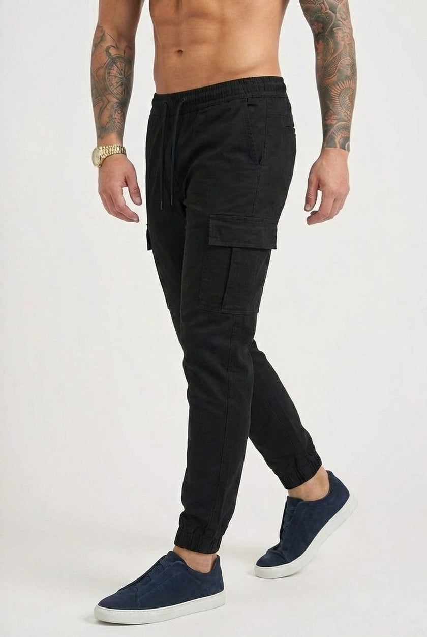 FJØRNA black cargo jogger trousers with multiple pockets, relaxed fit, and elastic cuffs, casual streetwear style.