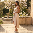 FJØRNA sleeveless wrap midi dress with asymmetric hem, shown in a stylish, flowing design on a model.
