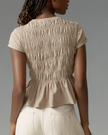 FJØRNA women's linen top with ruffle detail, showcasing lightweight, breathable fabric and elegant design for stylish summer wear.