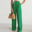 Lightweight high-waisted wide-leg pleated summer trousers for women by FJØRNA, shown in a natural fabric with a relaxed fit.