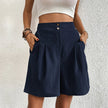 FJØRNA women's lightweight summer shorts with high waist and wide-leg pleated design, shown in neutral fabric on a model.