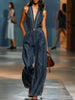 Dark blue denim FJØRNA jumpsuit with V-neck, sleeveless design, and wide-leg silhouette displayed on a hanger.